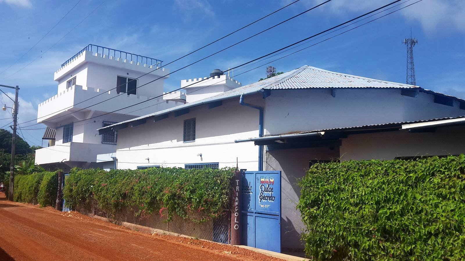 White two-story building with blue details on a quiet street in Las Galeras