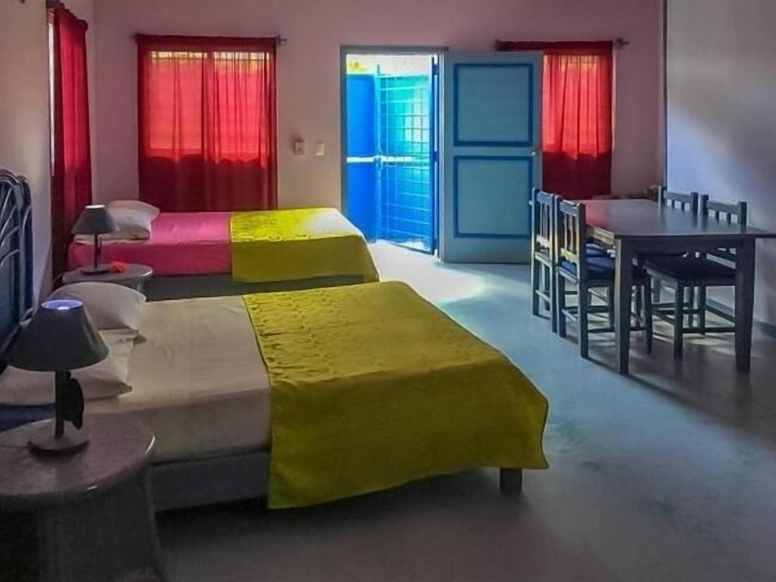 Spacious room with two beds, a dining table and red curtains